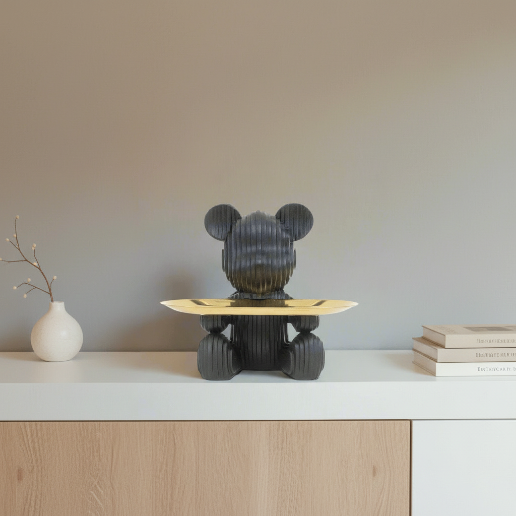 Black bear-shaped object with a gold platform on a plain background