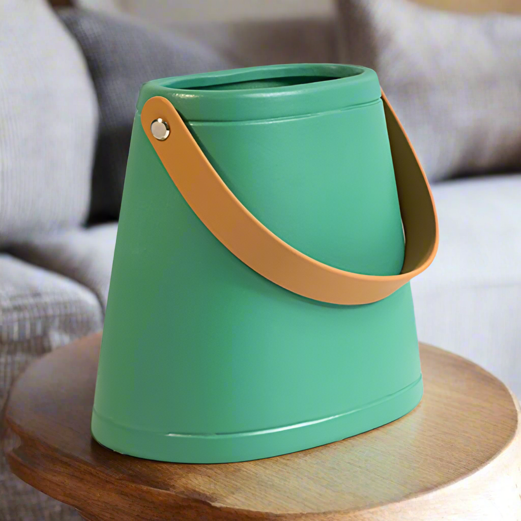 Green bucket with a brown handle on a wooden surface