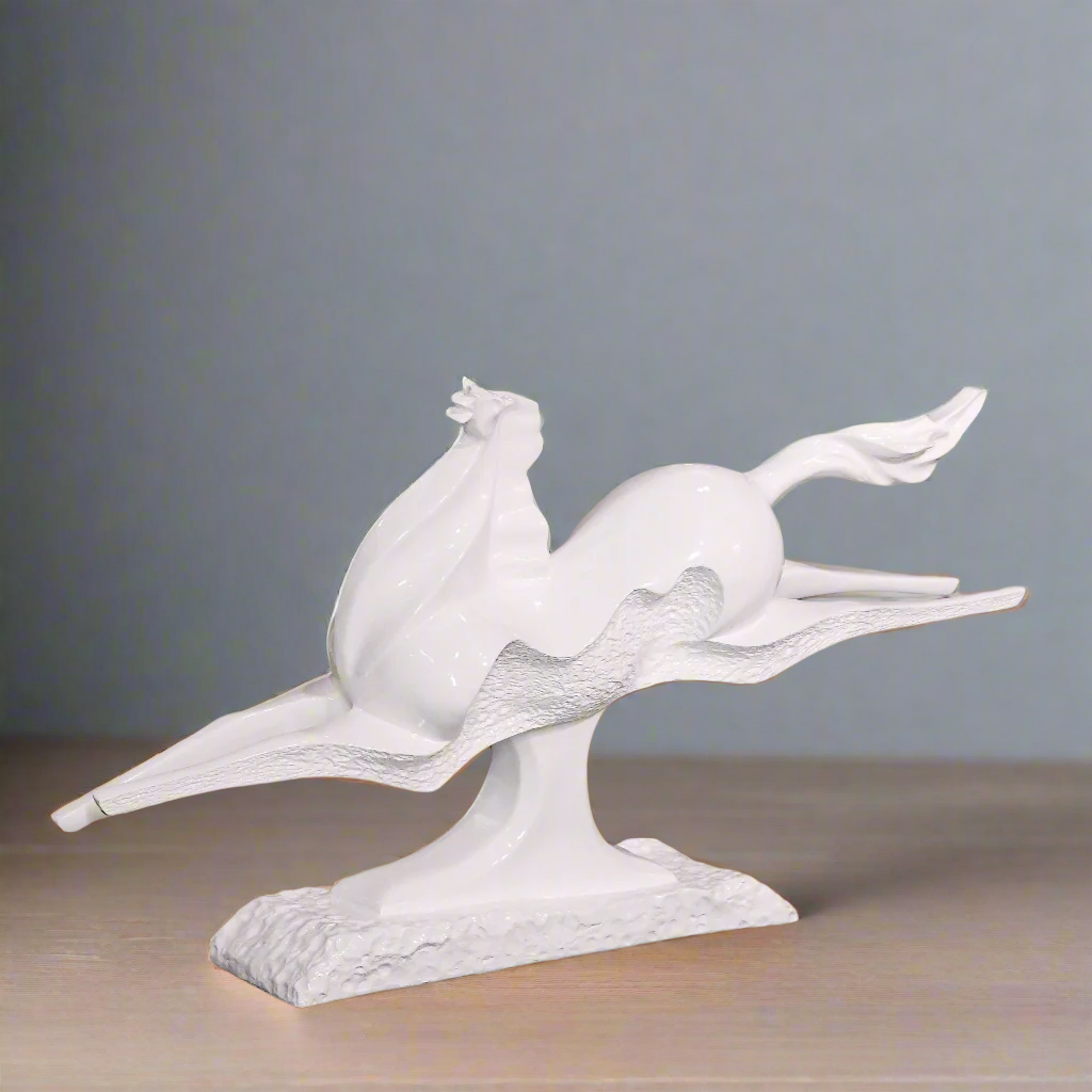 White ceramic sculpture of a bird on a branch with a blurred indoor background