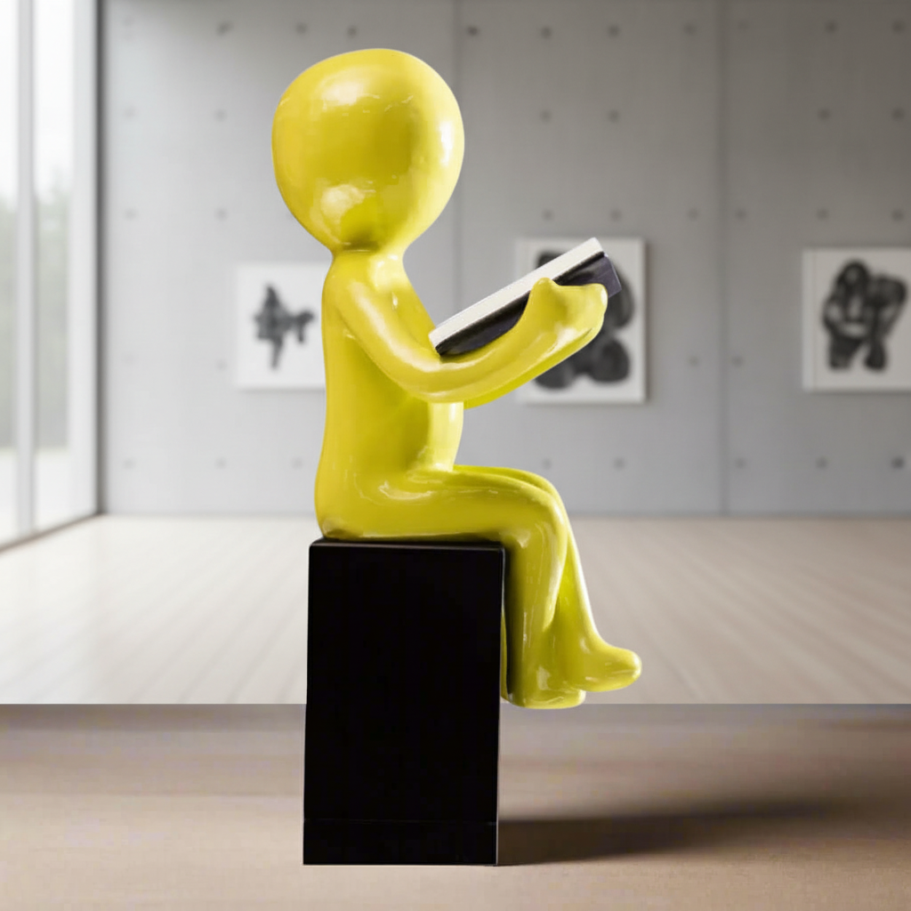 green ceramic figure of a person reading a book on a black pedestal against a gray background