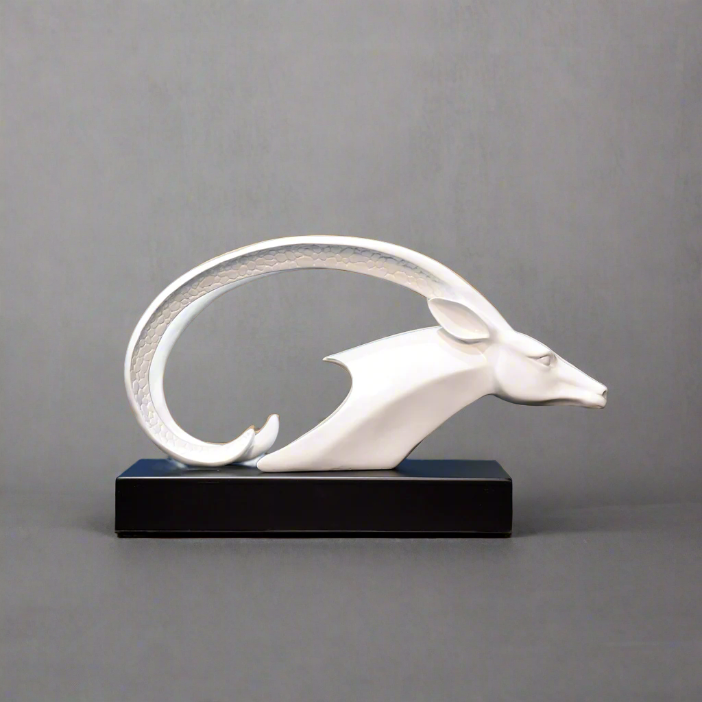 White decorative animal sculpture on a wooden surface with abstract art in the background