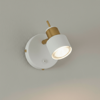 Wall-mounted light fixture with white shade and gold accents on a neutral wall.