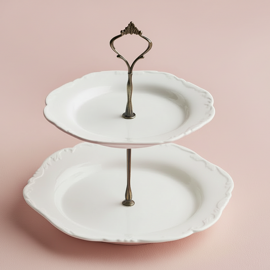 Two-tiered ceramic cake stand with decorative metal holder on a pink background