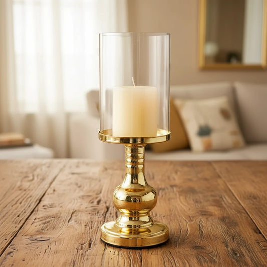 Gold candle holder with a white candle on a wooden table in a living room setting.