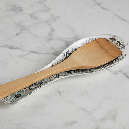 Wooden spatula on a floral-patterned ceramic plate against a marble background