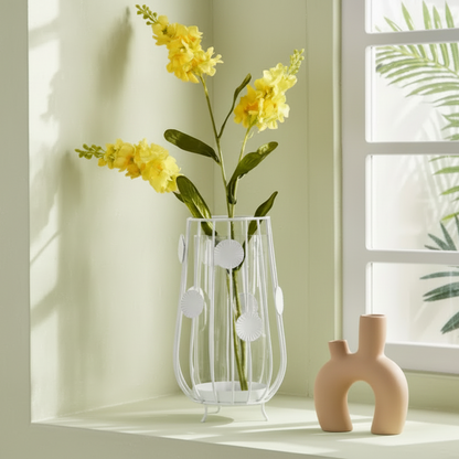 Decorative vase with yellow flowers on a windowsill with light streaming through.