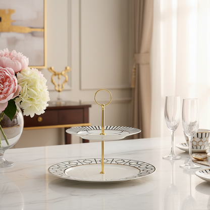 Two-tiered ceramic cake stand with geometric design and gold accents on a gray background
