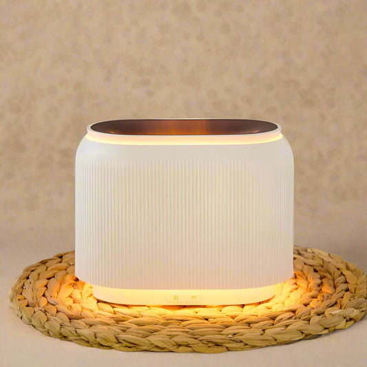 An electric diffuser with flame-like lighting on a woven mat, predominantly white in color.