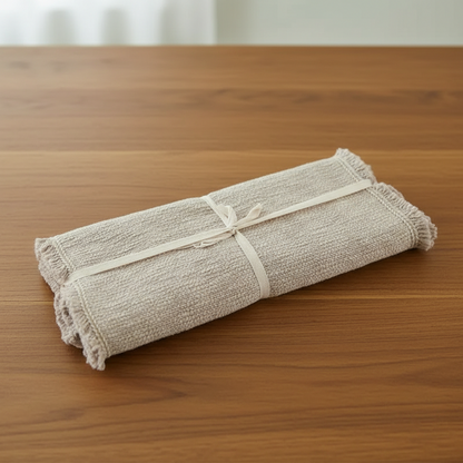 Rolled-up beige towel tied with a white ribbon on a wooden surface