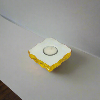 Decorative candle holder with yellow base and white top on a neutral surface