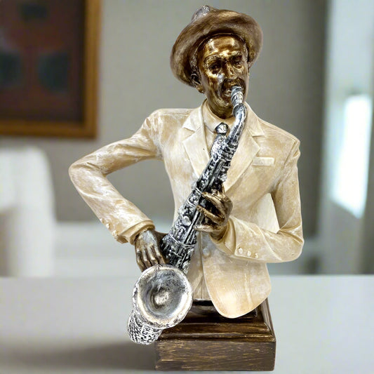 A vintage-style sculpture of a musician playing the saxophone, wearing a hat and suit. The sculpture is primarily in shades of white and gold with a focus on the saxophone details.