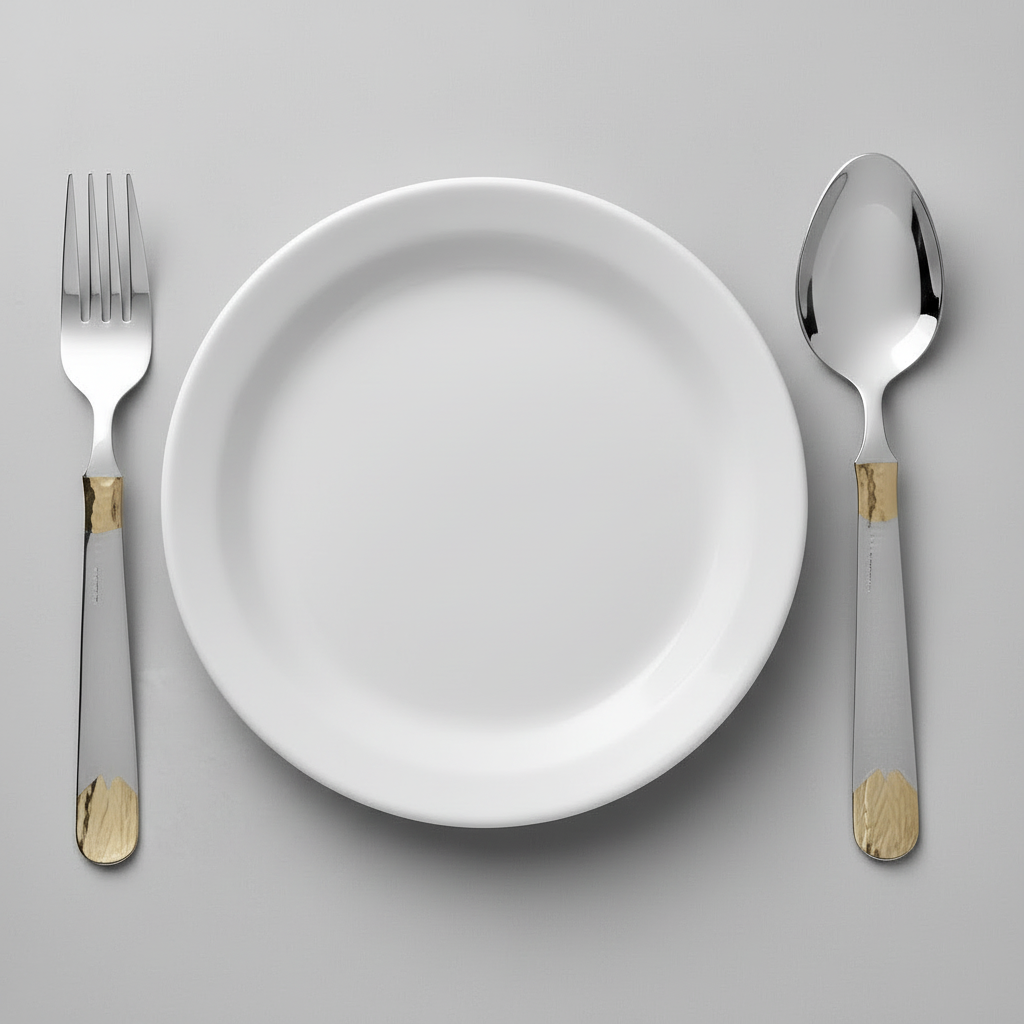 White plate with silver fork and spoon on a gray background