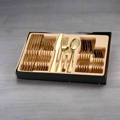 Set of gold cutlery in a black case on a green surface