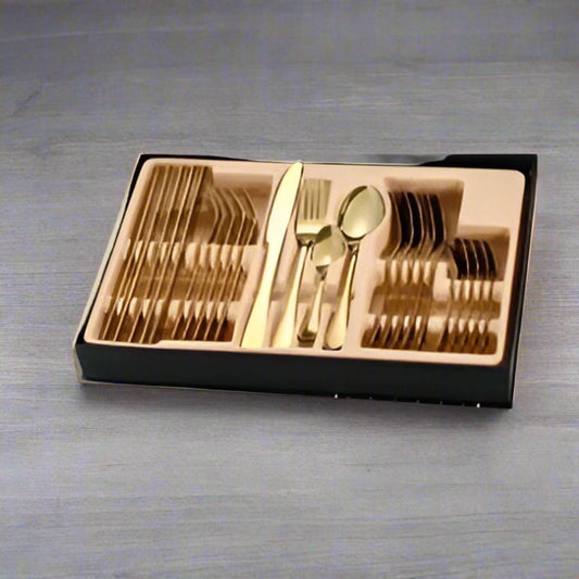 Set of gold cutlery in a black case on a green surface
