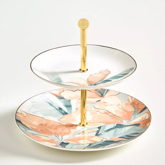 Two-tiered ceramic tray with floral design and gold stand on a white background