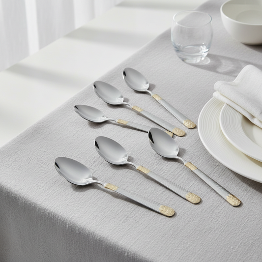 Set of silver spoons with gold accents on a tablecloth