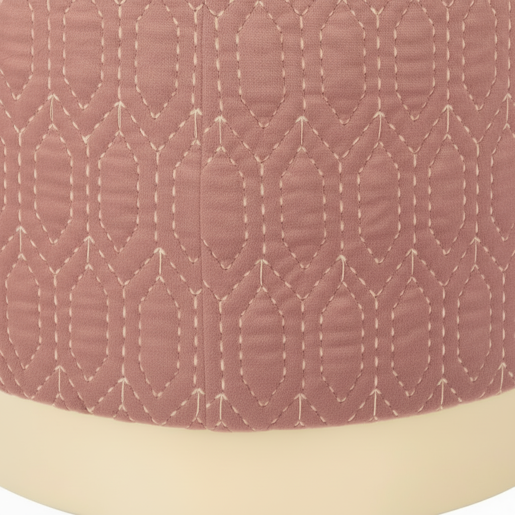 Close-up of a quilted fabric with a geometric pattern on a pink background