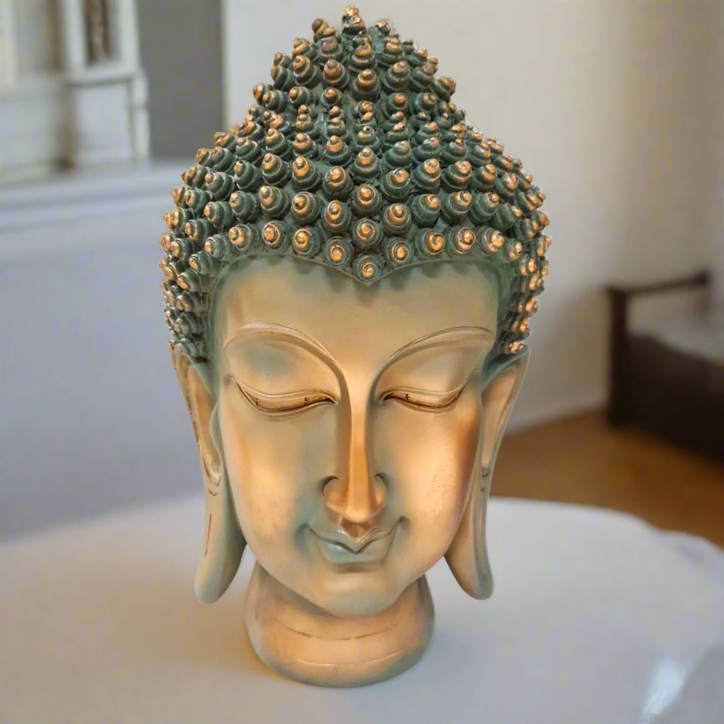 Bronze Buddha head with intricate design on a white background
