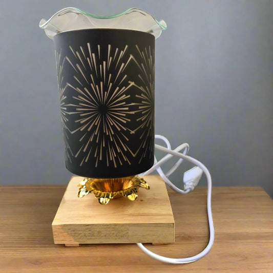 Decorative lamp with black shade and gold design on a wooden base, plugged into a white cable.