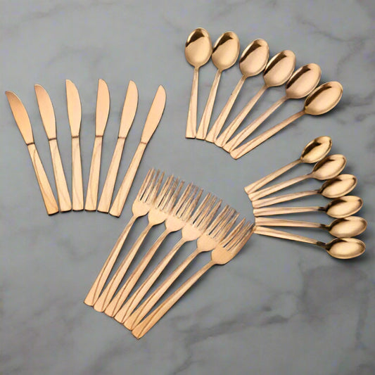 Set of gold-colored cutlery including knives, forks, and spoons on a black background
