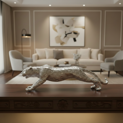A metallic silver leopard figurine sculpture displayed on a dark wooden console table in a modern, elegant living room setting.