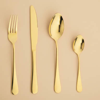 Set of gold cutlery including fork, knife, and two spoons on a beige background