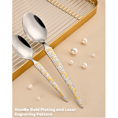 Two silver spoons with gold handles and laser engraving on a beige surface with pearls.