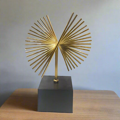Decorative gold sculpture on a black base against a white background