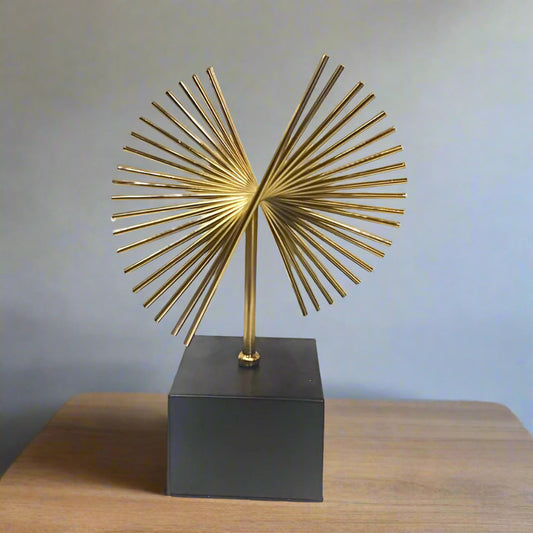 Decorative gold sculpture on a black base against a white background