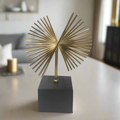 A gold metal palm tree sculpture on a black base, with a white background.