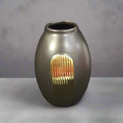 A round black ceramic vase with a textured gold accent on a dark background.