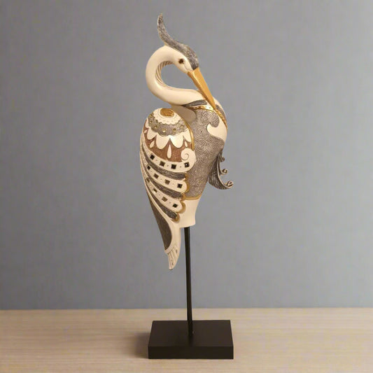 Decorative heron sculpture on a stand against a gray background