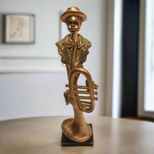 Bronze statue of a person playing a tuba on a table with a blurred background