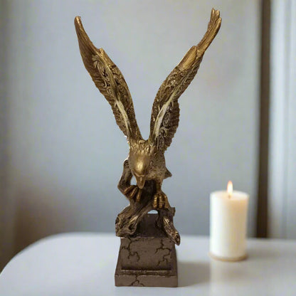 Bronze eagle sculpture on a white surface with a blurred candle in the background