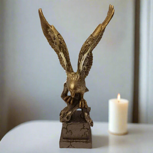 Bronze eagle sculpture on a white surface with a blurred candle in the background