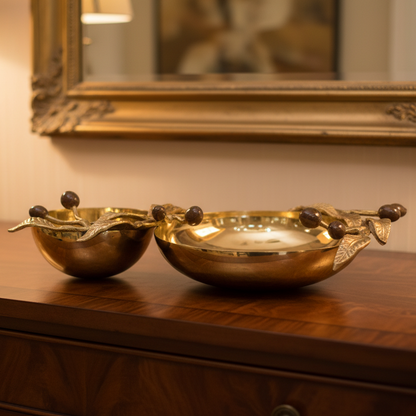 Pair of gold decorative bowls on a wooden surface with a mirror in the background.