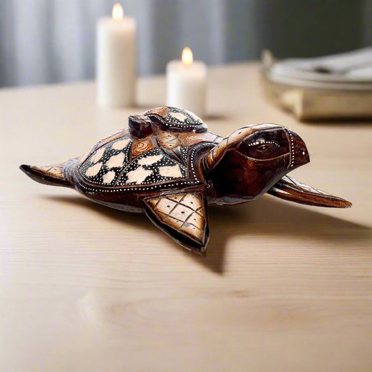 Decorative turtle figurine on a wooden surface with candles in the background