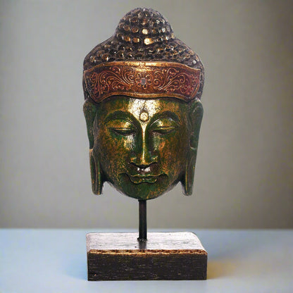 Bronze Buddha head sculpture on a stand with a plain background