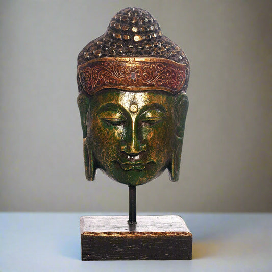 Bronze Buddha head sculpture on a stand with a plain background