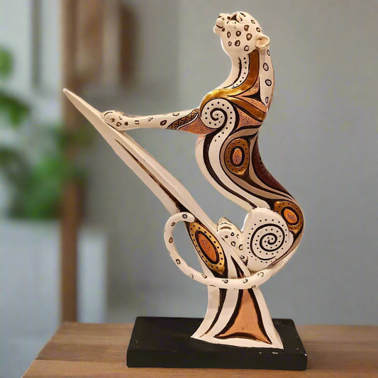 Decorative sculpture of a cat on a sword with intricate patterns on a wooden surface.