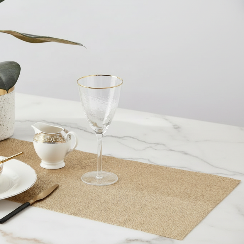 Wine glass and small pitcher on a woven placemat with marble surface