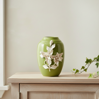 Green vase with floral design on a wooden surface against a beige wall