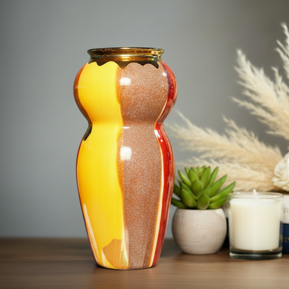 Decorative vase with a unique design on a table with plants and candles.