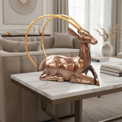 Bronze deer statue with gold antlers on a marble table in a living room.