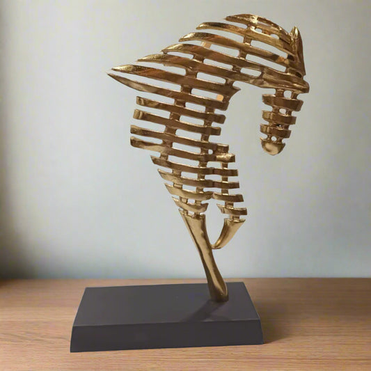 Gold seahorse sculpture on a black base against a white background