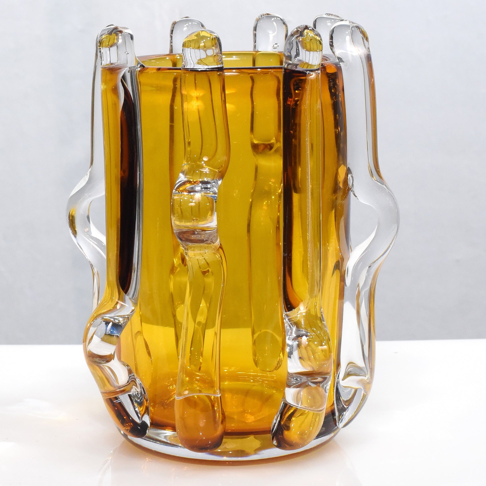 Glass pitcher filled with a yellow liquid on a white background