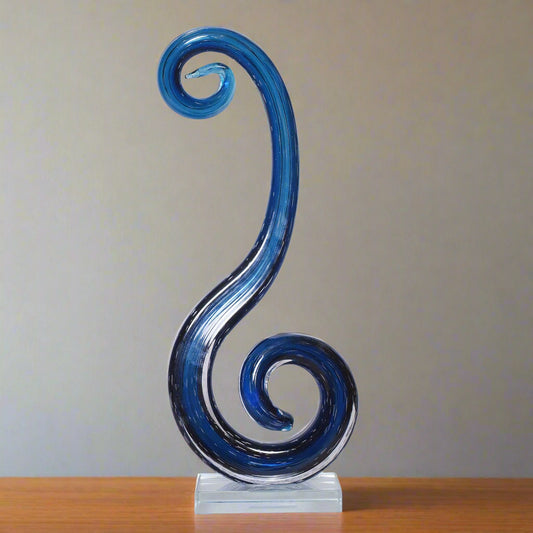 Blue glass sculpture on a stand against a beige background
