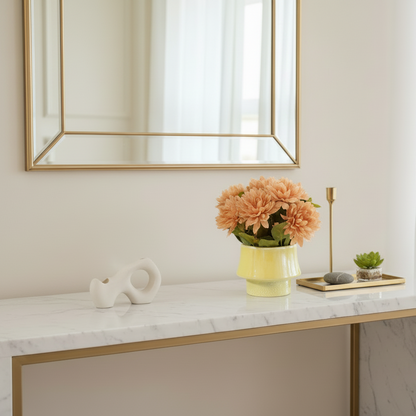 Decorative table with a vase of flowers, small sculpture, and candle on a marble surface.