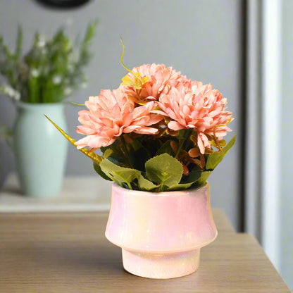 Pink artificial flowers in a pink vase on a yellow background