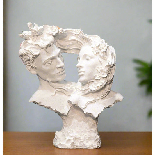 White sculpture of two faces intertwined against a blue wall.